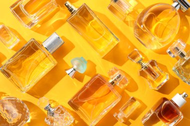 Sarı arka planda çeşitli parfüm şişeleri, düz yatıyordu.