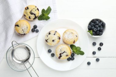 Yaban mersinli leziz çörekler, pudra şekeri ve beyaz ahşap masa üzerinde nane şekeri.