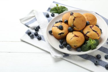 Yaban mersinli lezzetli kekler ve beyaz ahşap masada nane şekeri, yakın plan. Metin için boşluk