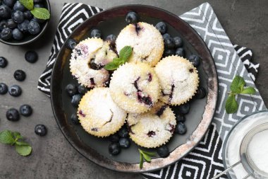 Yaban mersinli lezzetli çörekler, pudra şekeri ve siyah desenli masada nane şekeri.