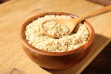 Kahverengi pirinç ve kaşık kasede, ahşap masada, yakın plan.