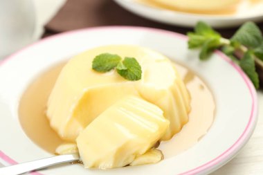 Karamel soslu lezzetli puding ve beyaz masada servis edilen nane şekeri.