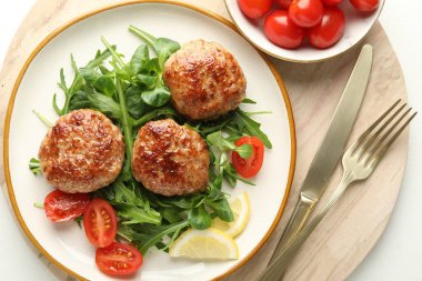 Yeşillikli, domatesli ve çatal bıçaklı leziz börekler beyaz masada.