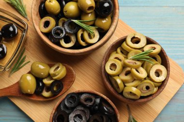 Farklı lezzetlerde marine edilmiş zeytin halkaları, tüm olanlar ve biberiye açık mavi ahşap masa, üst manzara