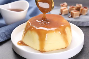 Gri masadaki pudingin üzerine karamel sosu dök.