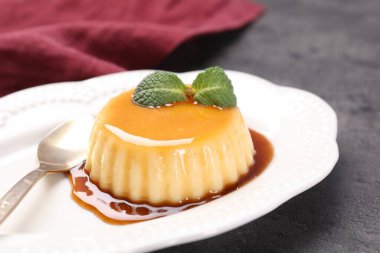 Gri masada servis edilen karamel soslu ve naneli lezzetli puding.