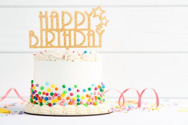 Lezzetli bento keki, üzerine renkli süsler serpiştirilmiş, beyaz masa üzerinde serpentin şeritler, yakın plan. Metin için boşluk