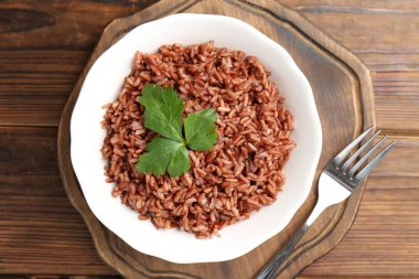 Ahşap masada servis edilen maydanozlu lezzetli kahverengi pirinç.