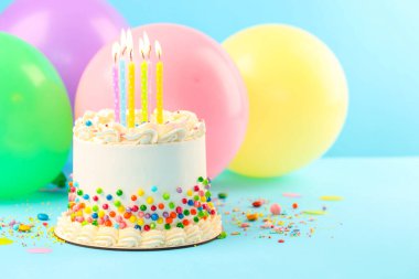 Renkli şekerli nefis bento keki ve açık mavi masada yanan mumlar, yakın plan. Metin için boşluk