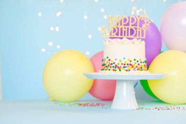 Renkli süslemeli nefis bento keki ve bulanık ışıklara karşı açık mavi masada mutlu yıllar. Metin için boşluk