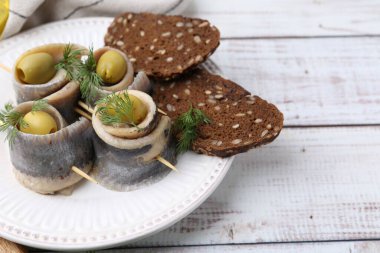 Zeytinli lezzetli ringa dürümleri, beyaz ahşap masada dereotu ve ekmek, yakın plan. Metin için boşluk