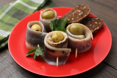 Lezzetli ringa dürümleri zeytin, maydanoz ve ekmek ahşap masada, yakın plan.