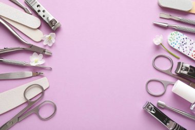 Pembe arka planda farklı manikür aletleri ve çiçekler var. Metin için boşluk