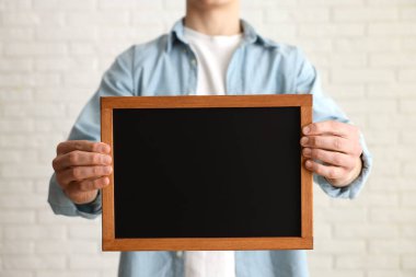 Kapalı alanda boş küçük tahta tutan adam, yakın plan.