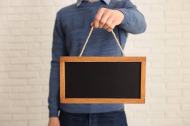 Kapalı alanda boş küçük tahta tutan adam, yakın plan.