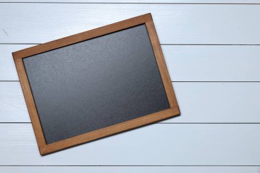 Beyaz ahşap zemin üzerinde boş küçük karatahta, üst görünüm