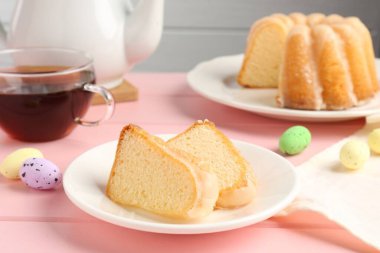 Lezzetli kek parçaları, pembe ahşap masada paskalya yumurtası ve çay, yakın plan.