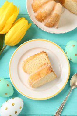 Lezzetli kek parçaları, paskalya yumurtaları ve laleler açık mavi ahşap masa, düz yatıyordu.