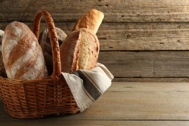 Hasır sepetteki farklı somunlar ahşap masada, metin için yer var.