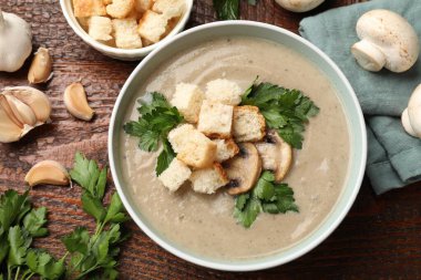 Lezzetli mantar kremalı çorba, kızarmış ekmek, maydanoz ve ahşap masa üzerindeki malzemeler.