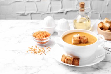 Lezzetli mercimek kremalı çorba ve beyaz mermer masada kızarmış ekmek.