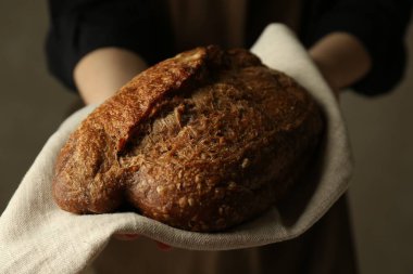 Gri arka planda taze ekmek somunu olan kadın, yakın plan.