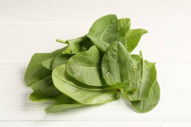 Taze yeşil kuş yaprakları beyaz ahşap masada, yakın plan.