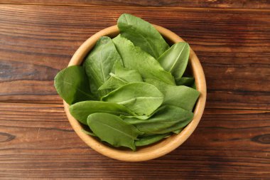 Taze yeşil kuş yaprakları kasede, ahşap masada, üst tarafta.