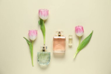 Parfüm şişeleri ve bej arka planda güzel çiçekler.