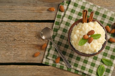 Tahta masada servis edilen nane ve tarçınlı, bademli lezzetli sütlaç. Metin için boşluk
