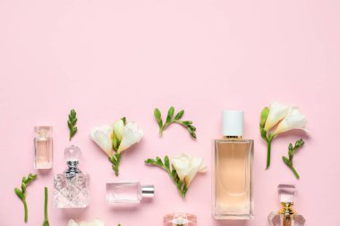 Parfüm şişeleri ve pembe arka planda güzel çiçekler. Metin için boşluk
