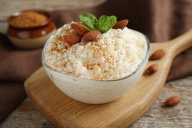 Tarçınlı lezzetli pirinç pudingi, ahşap masada nane ve badem, yakın plan.