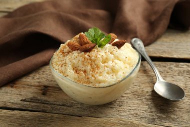 Tarçınlı lezzetli sütlaç, badem ve nane, ahşap masada servis edilir, yakın plan.