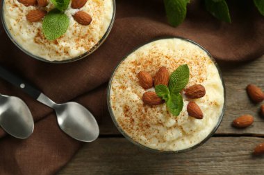 Tarçınlı lezzetli sütlaç, badem ve nane şekeri ahşap masada servis edilir.