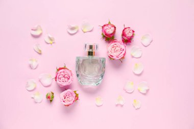 Bir şişe parfüm ve pembe arka planda güzel çiçekler.