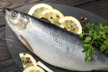 Ahşap masada tuzlanmış ringa balığı ve baharat, üst manzara.