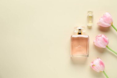 Parfüm şişeleri ve bej arka planda güzel çiçekler. Metin için boşluk