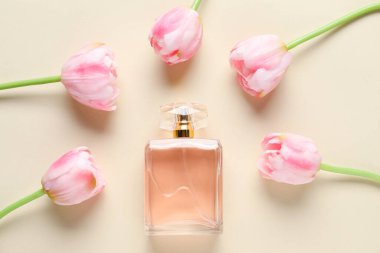 Bir şişe parfüm ve bej arka planda güzel çiçekler.