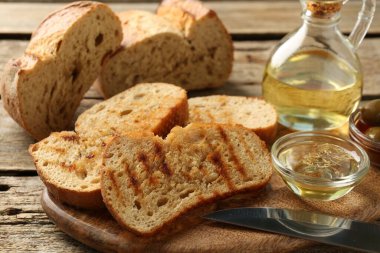 Ahşap masada yağlı, zeytinli ve baharatlı tost ekmeği yakın plan.