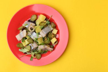 Sarı arka planda ringa balıklı nefis salata, üst manzara. Metin için boşluk