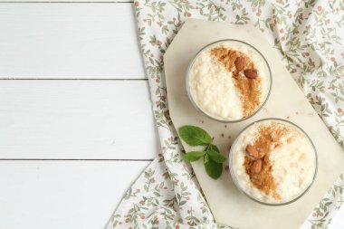 Tarçınlı lezzetli pirinç pudingi, beyaz ahşap masa üzerinde nane şekeri, üst manzara. Metin için boşluk