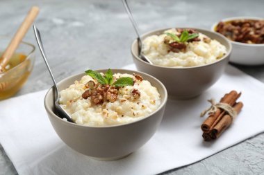 Cevizli, tarçınlı, nane ve ballı lezzetli sütlaç. Gri masada, yakın plan.