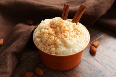 Tarçınlı lezzetli sütlaç ve ahşap masada badem, yakın plan.