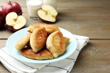 Ahşap masada elma ve sütle lezzetli pirizhky (doldurulmuş turtalar). Metin için boşluk