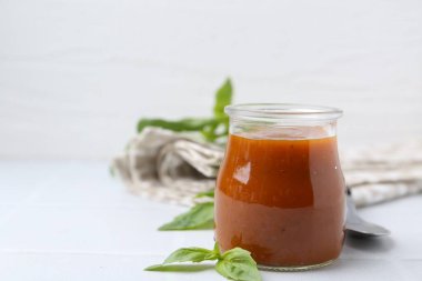 Cam kavanozda lezzetli köri sosu ve beyaz fayanslı masada fesleğen, yakın plan. Metin için boşluk