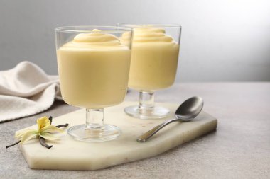 Lezzetli vanilyalı puding, kapsüller ve çiçekler gri masada.