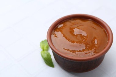 Lezzetli köri sosu ve fesleğen yaprakları beyaz fayanslı masada, yakın plan. Metin için boşluk