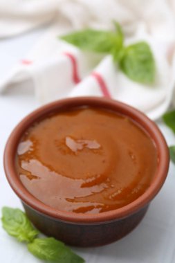 Lezzetli köri sosu ve fesleğen yaprakları beyaz fayanslı masada, yakın plan.