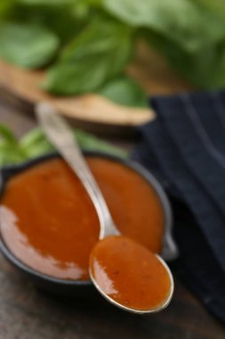 Lezzetli köri sosu ve fesleğen yaprakları ahşap masada, yakın plan.