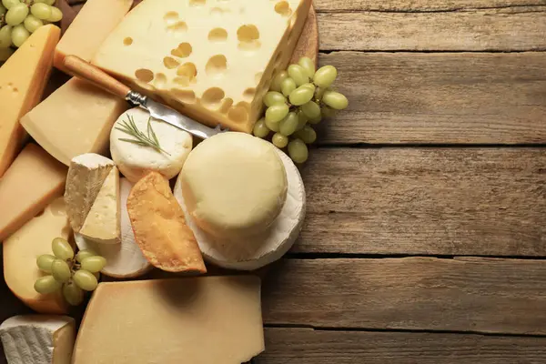 Farklı peynir türleri, biberiye ve üzümler ahşap masa, düz yatak. Metin için boşluk